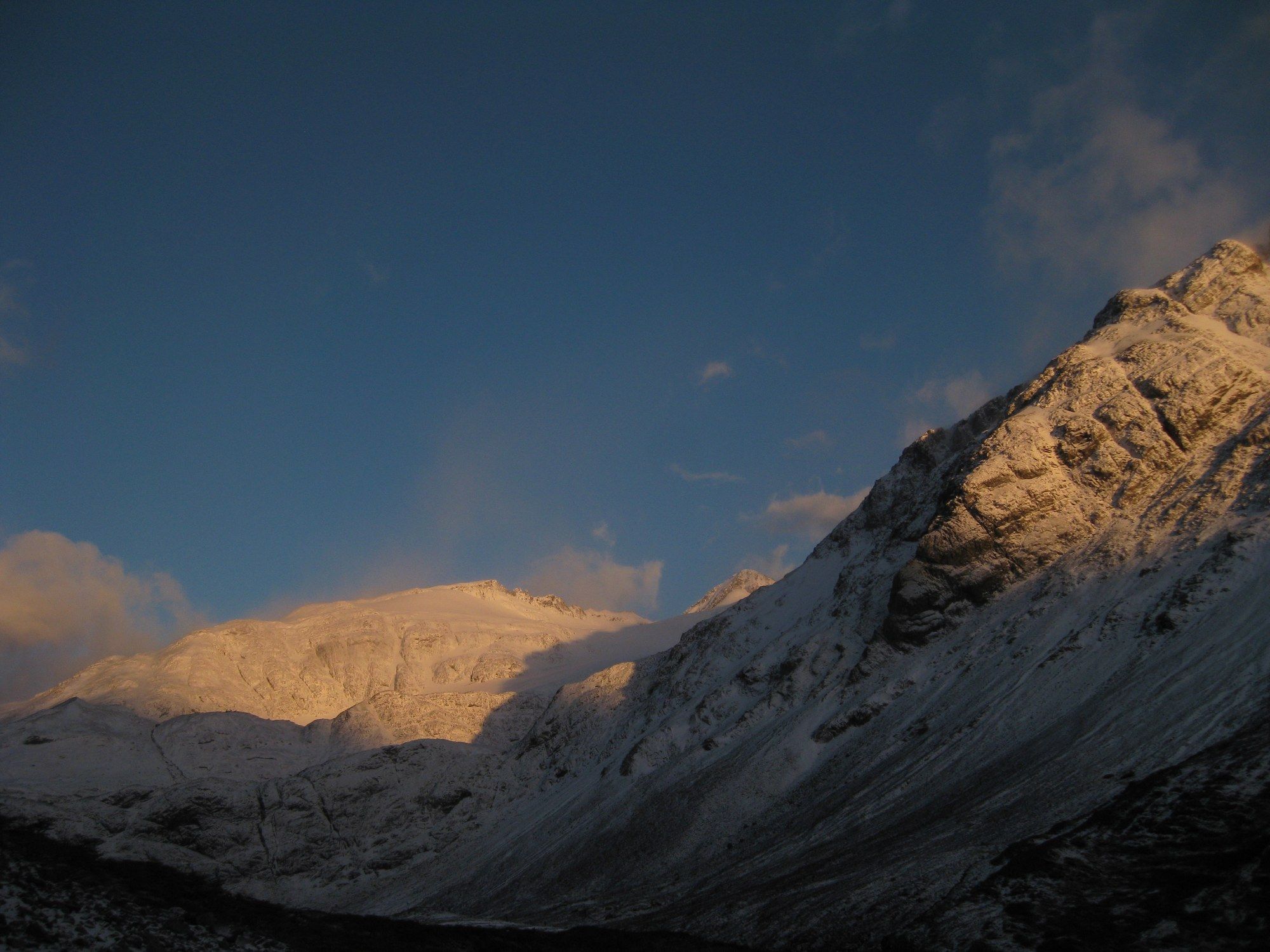 A snowy ridge catching the last gold light under a deep blue sky
