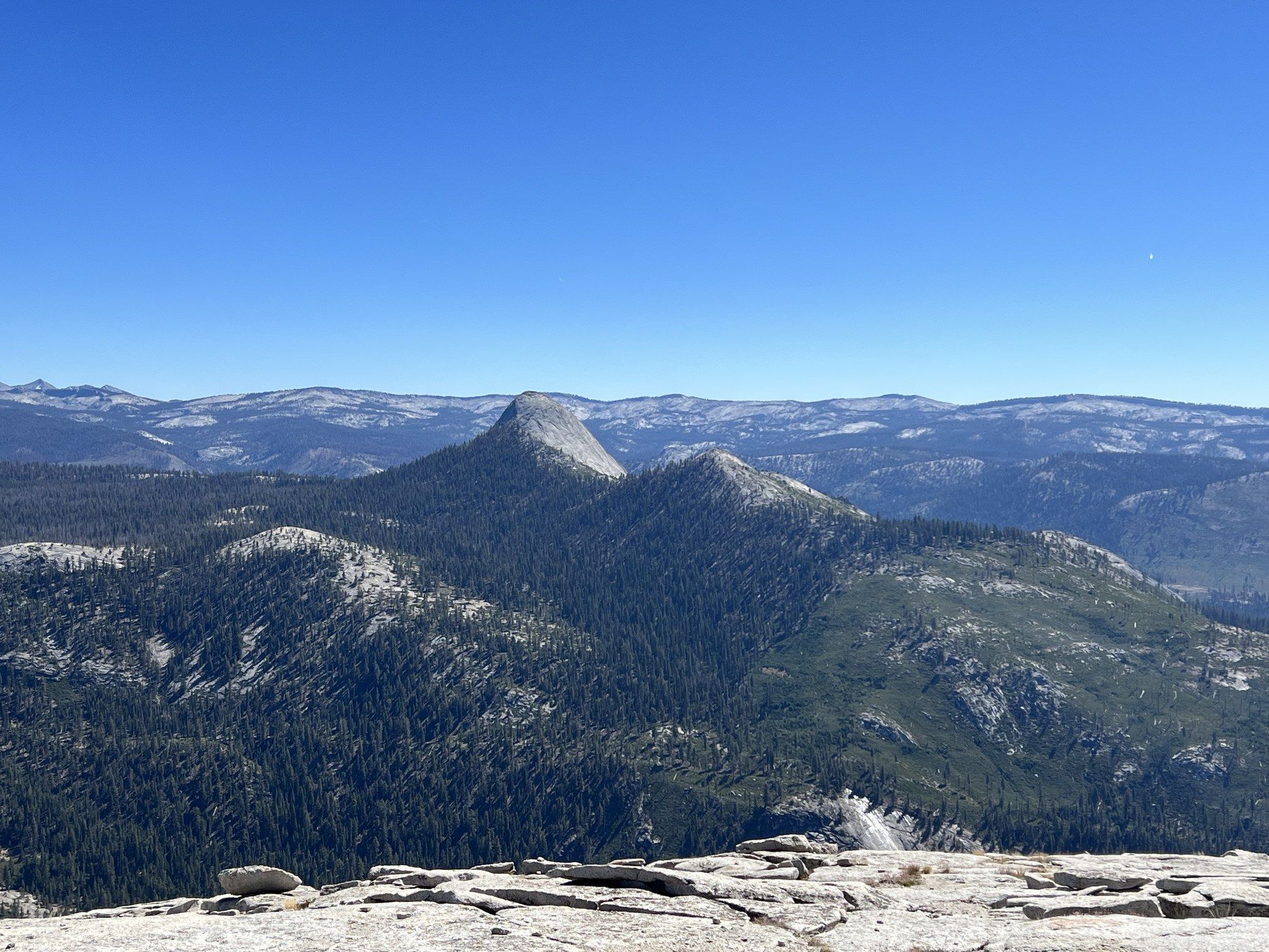 Yosemite's high country seen from the summit plateau of Half Dome, granite slabs in the foreground