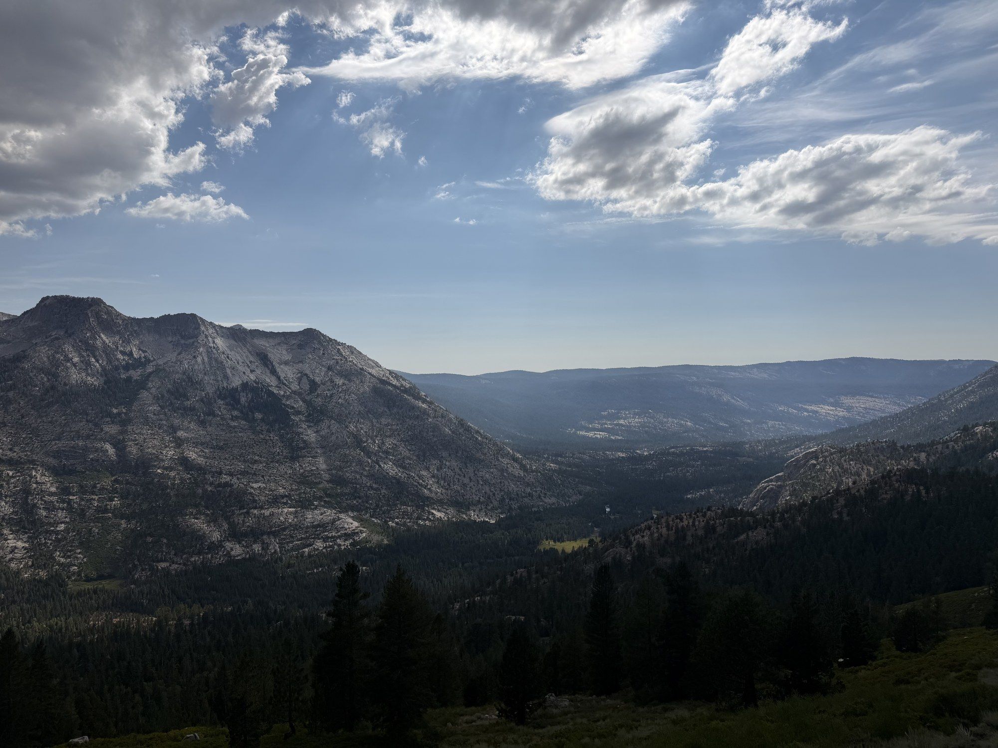 A Sierra valley of granite and forest opening out under afternoon cloud
