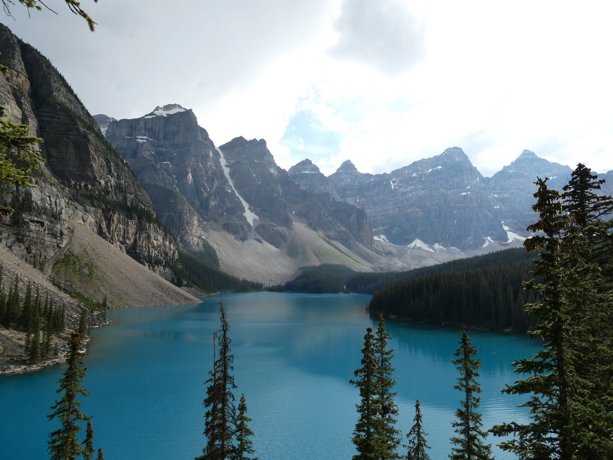 A turquoise glacial lake below a wall of snow-streaked peaks in Banff