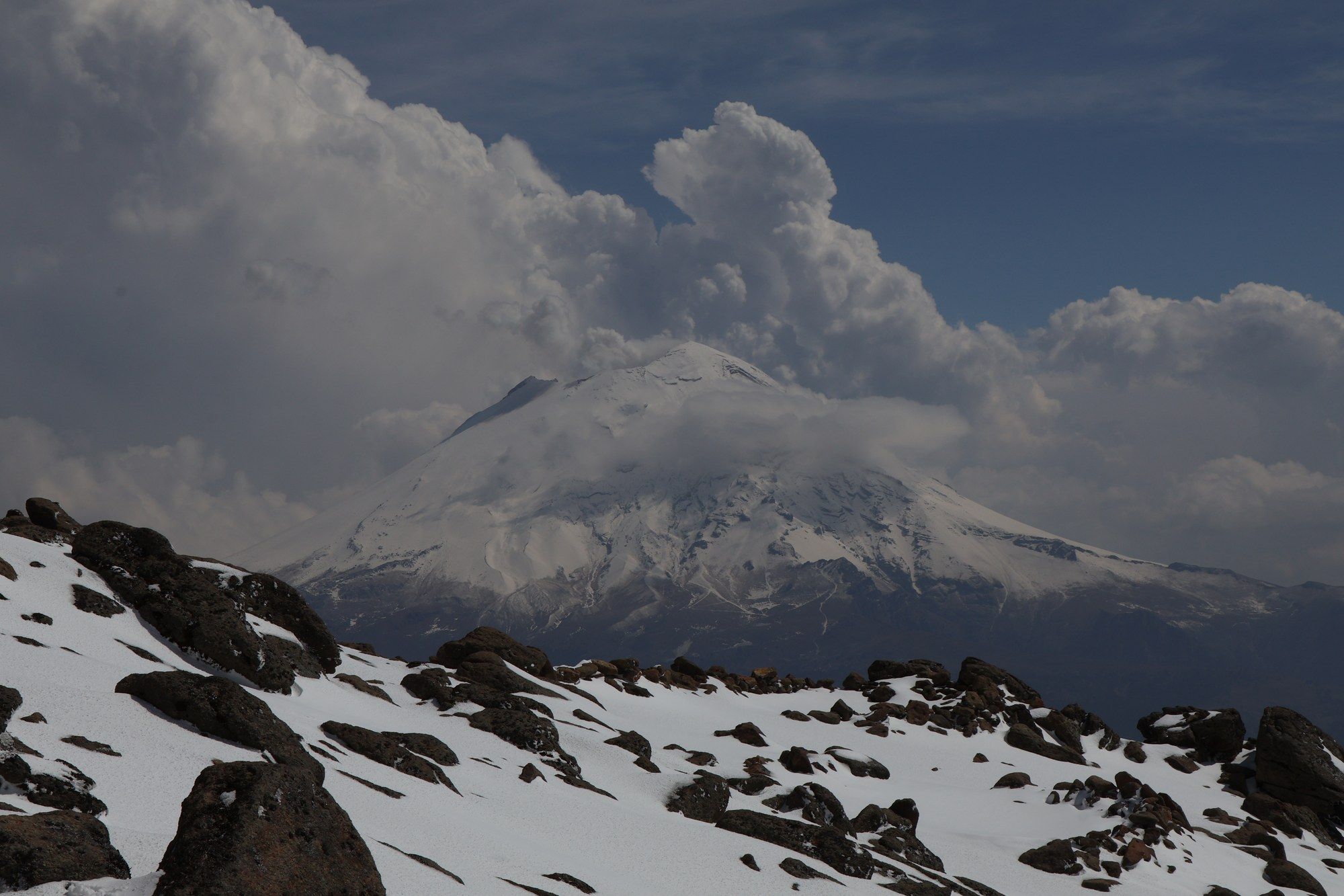Popocatepetl venting a plume of steam above the cloud layer