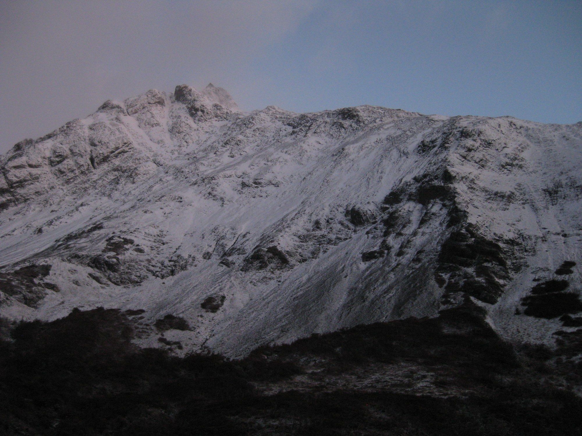 A snow-covered ridge in the last cold light before dark