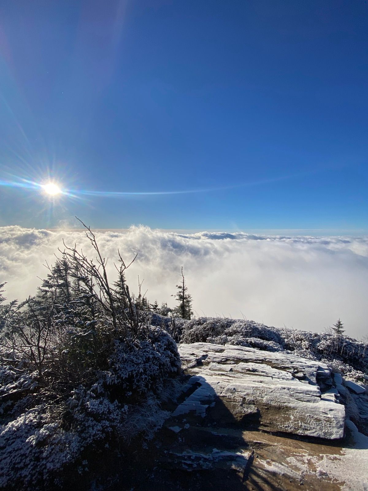 Sunlight over a snowy rock ledge and a sea of clouds