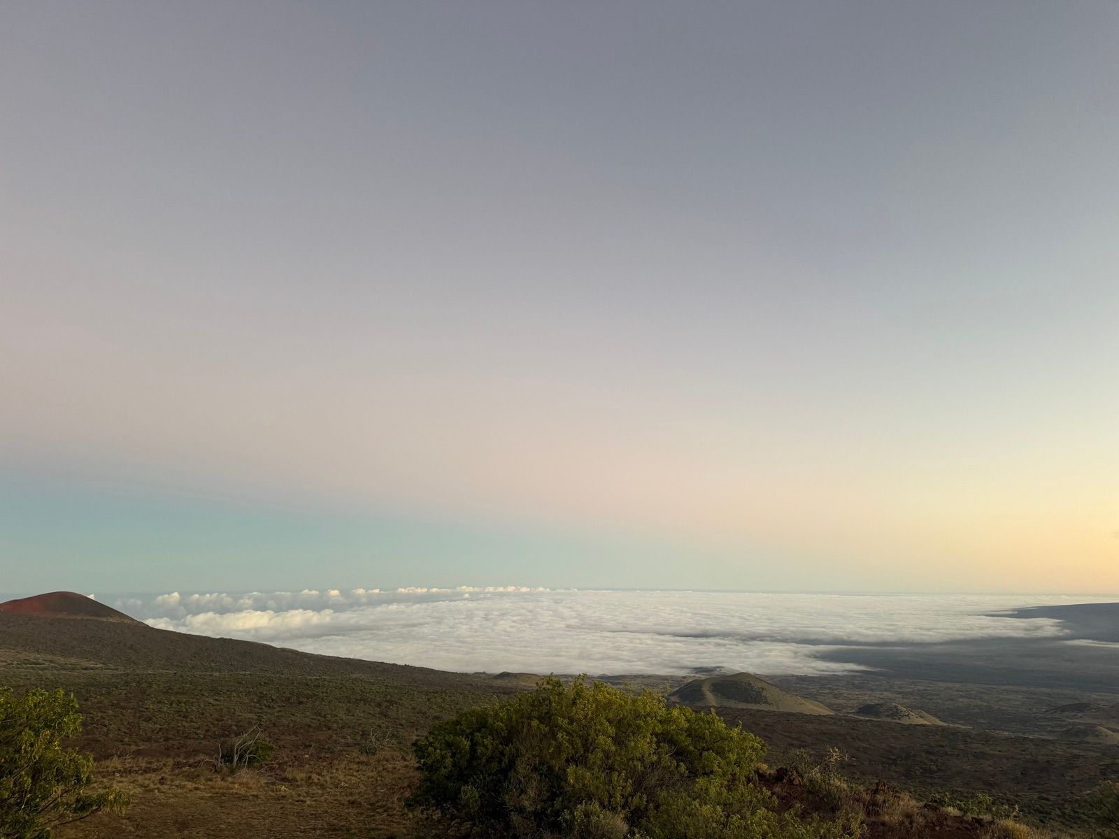 Cloud deck below a dark volcanic slope at dusk