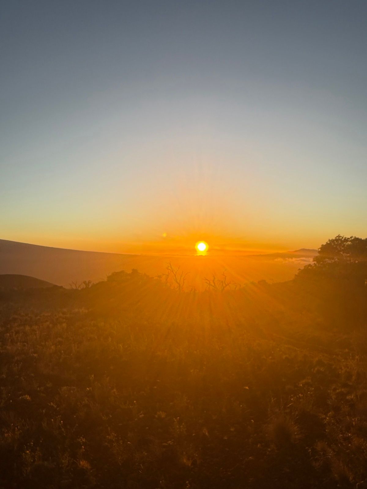 Sun setting over rolling volcanic slopes