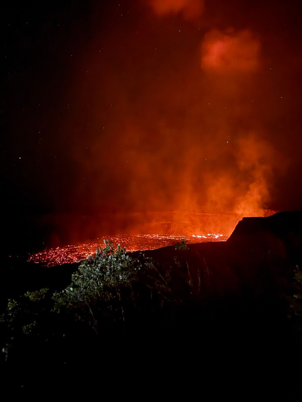 Orange lava glow rising from a volcanic crater at night
