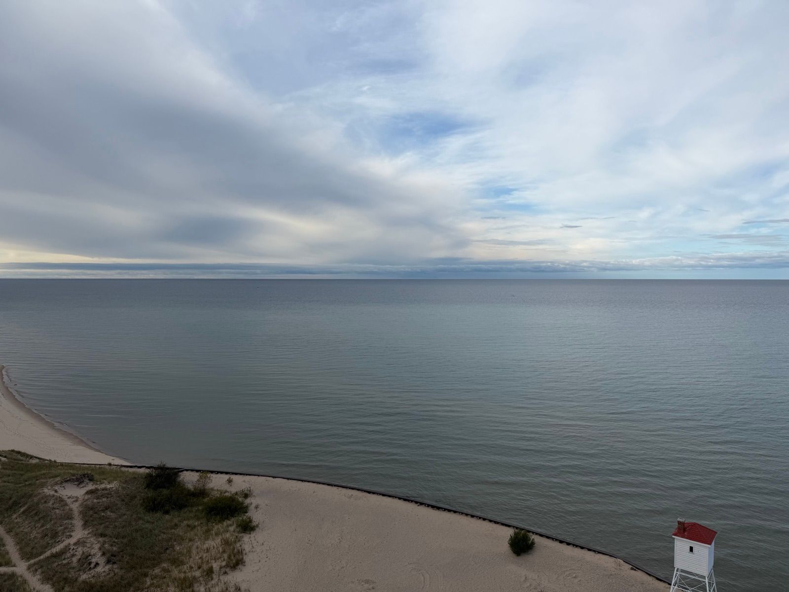 Lighthouse and beach seen from a high dune above calm water