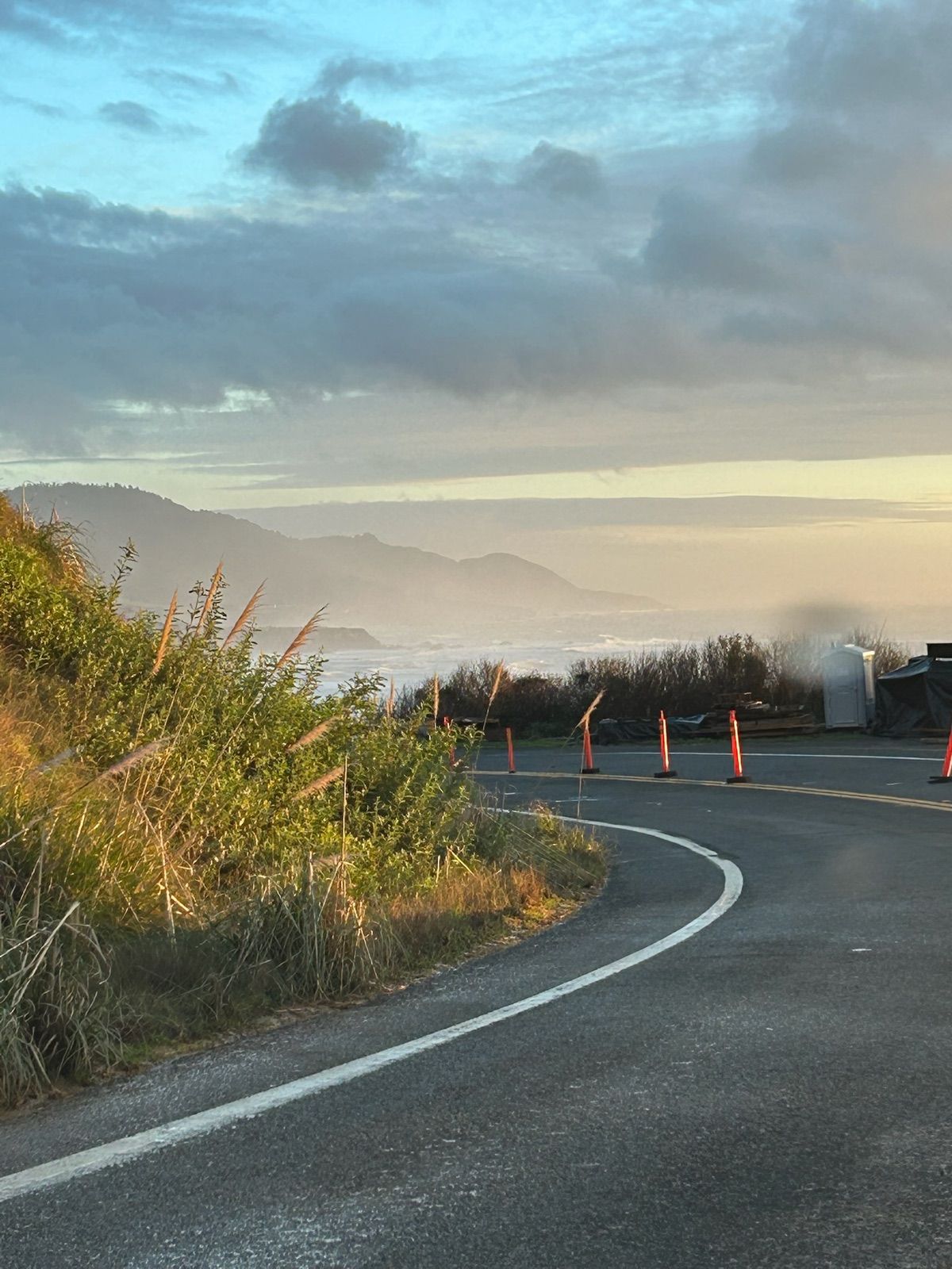 Coast highway curving toward fog in warm evening light