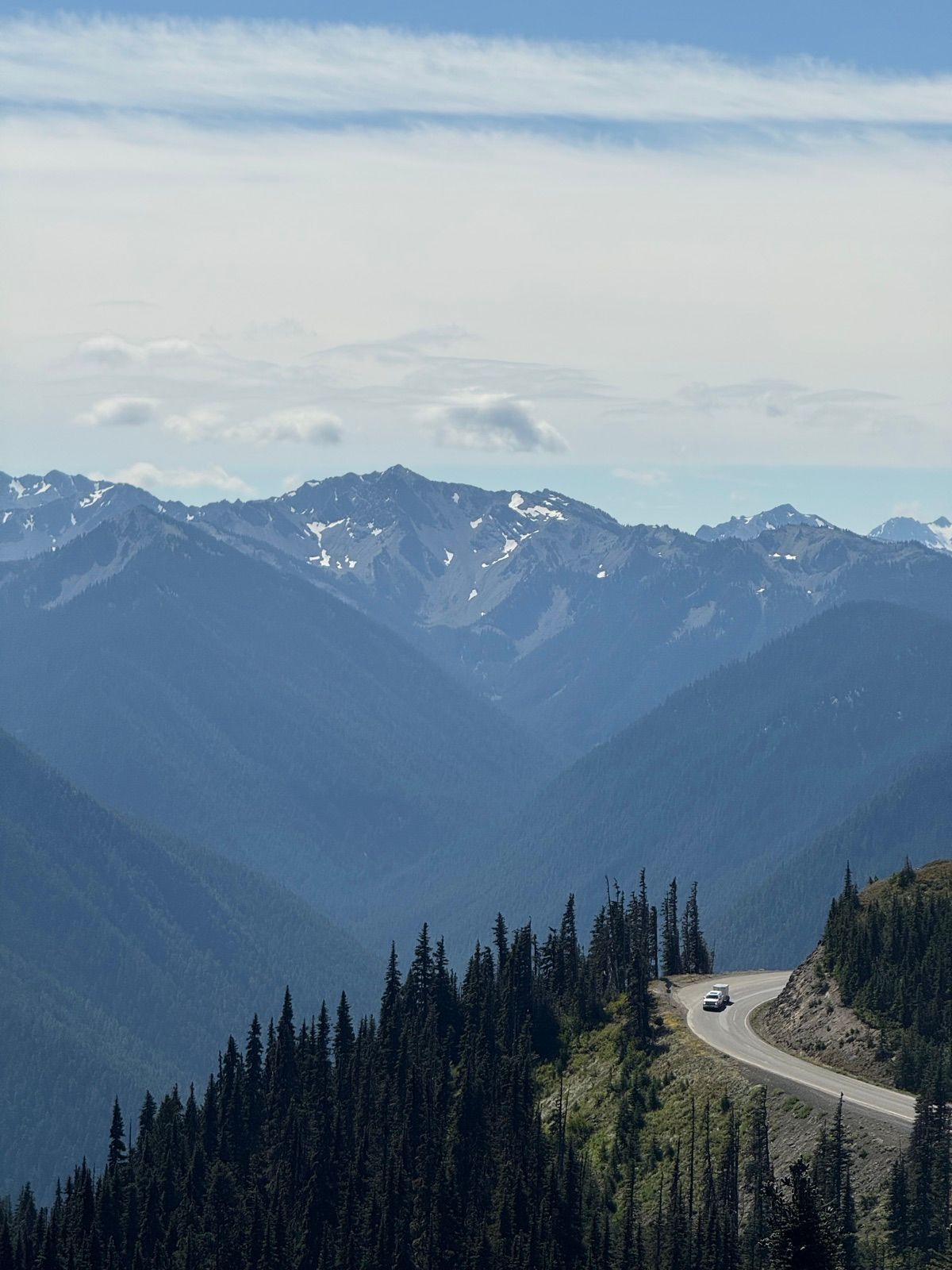 Mountain road curling along a ridge below snow-streaked peaks