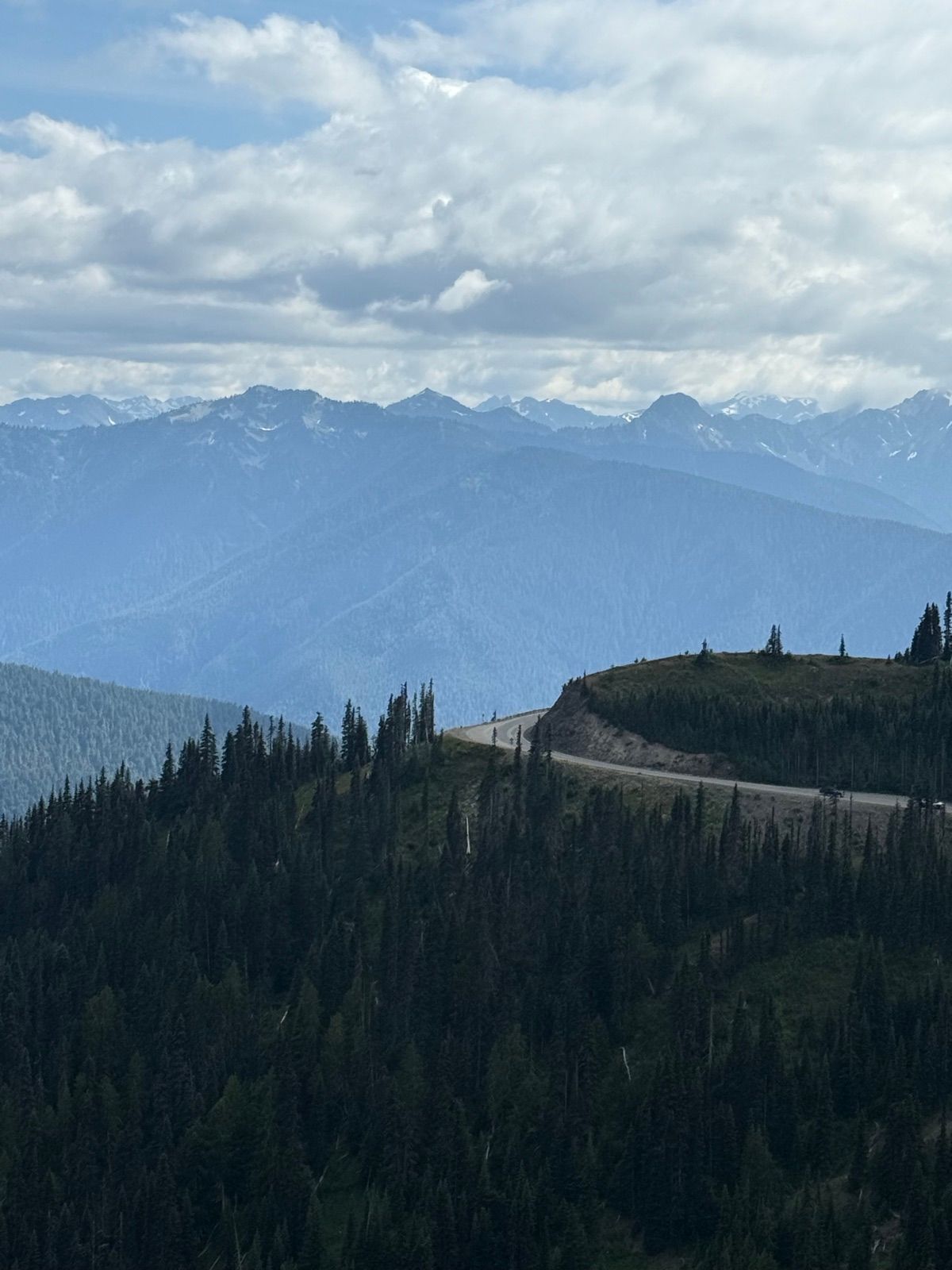 Road crossing an alpine ridge beneath broken clouds