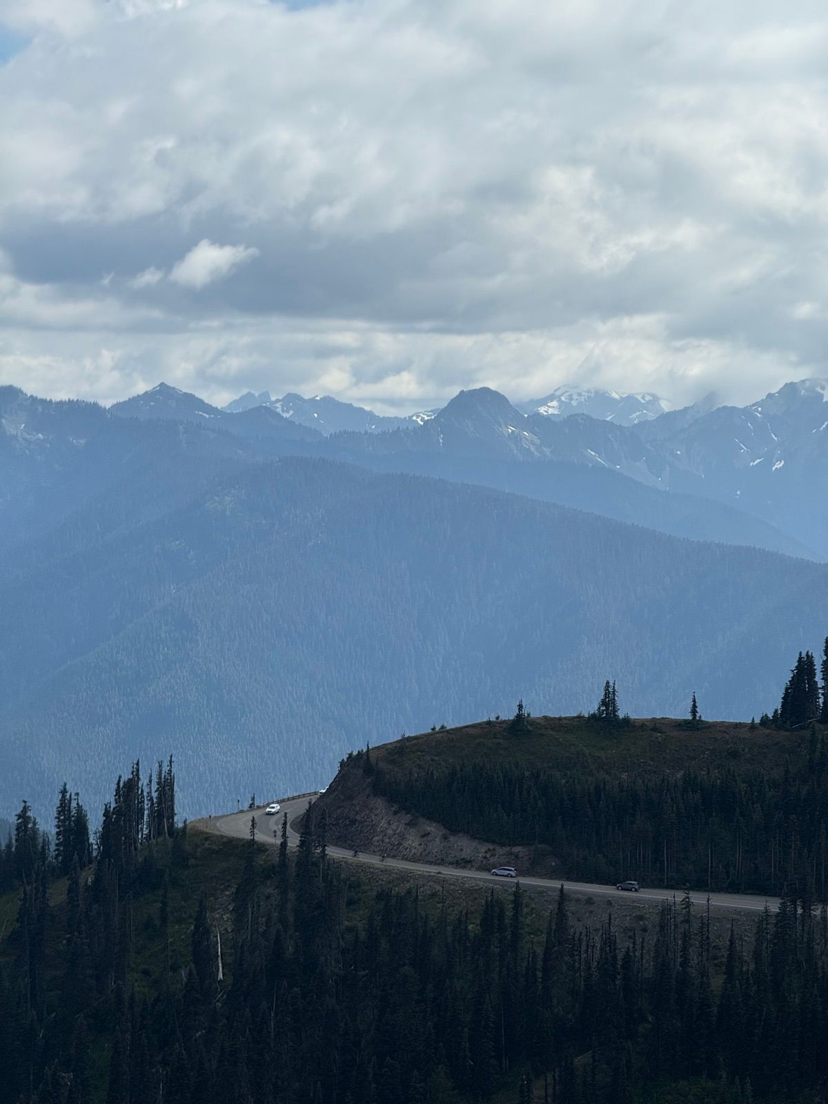 Cloudy Cascade peaks beyond a dark forested ridgeline