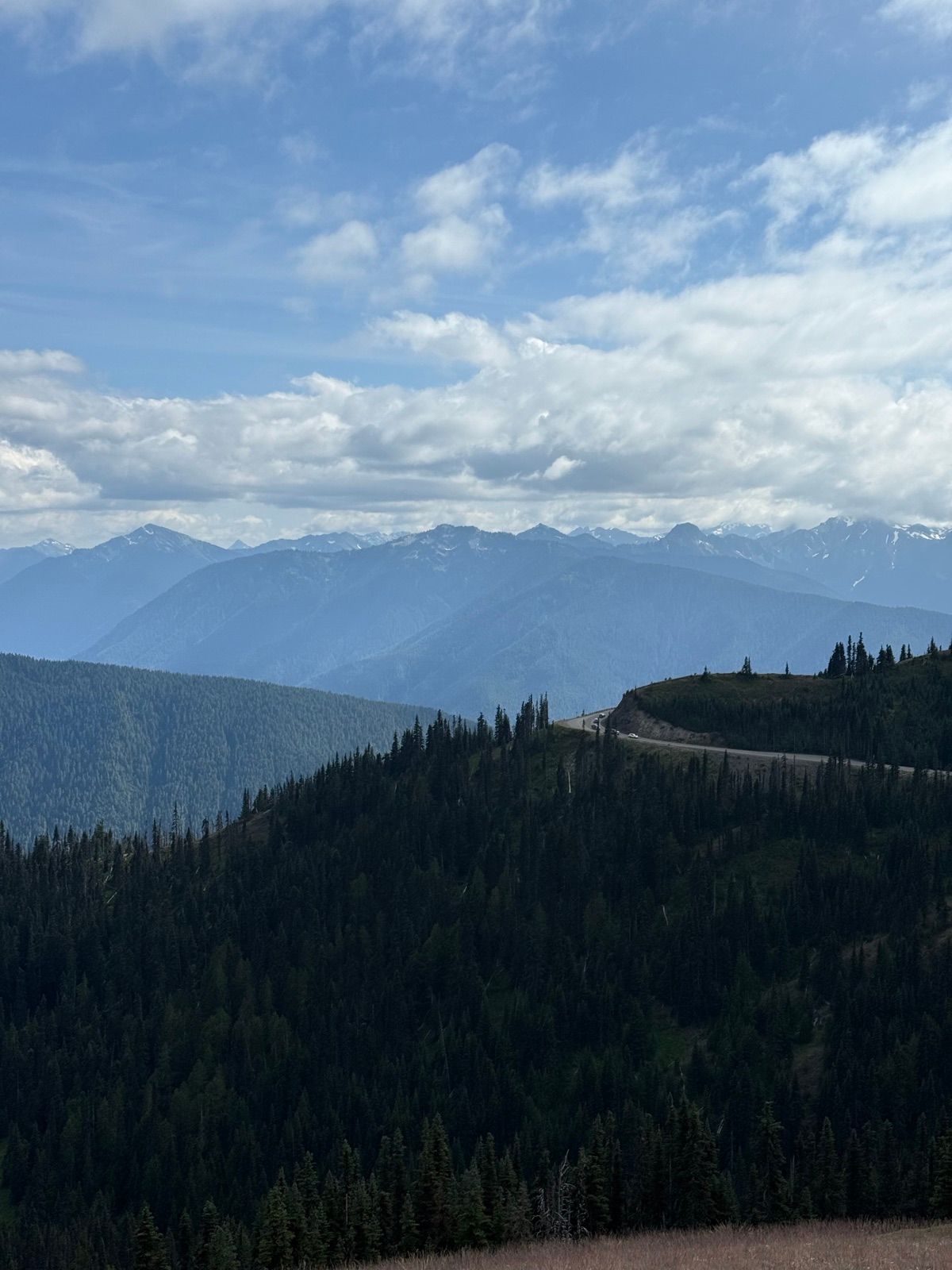 Layered blue mountain ridges beyond a curving high road