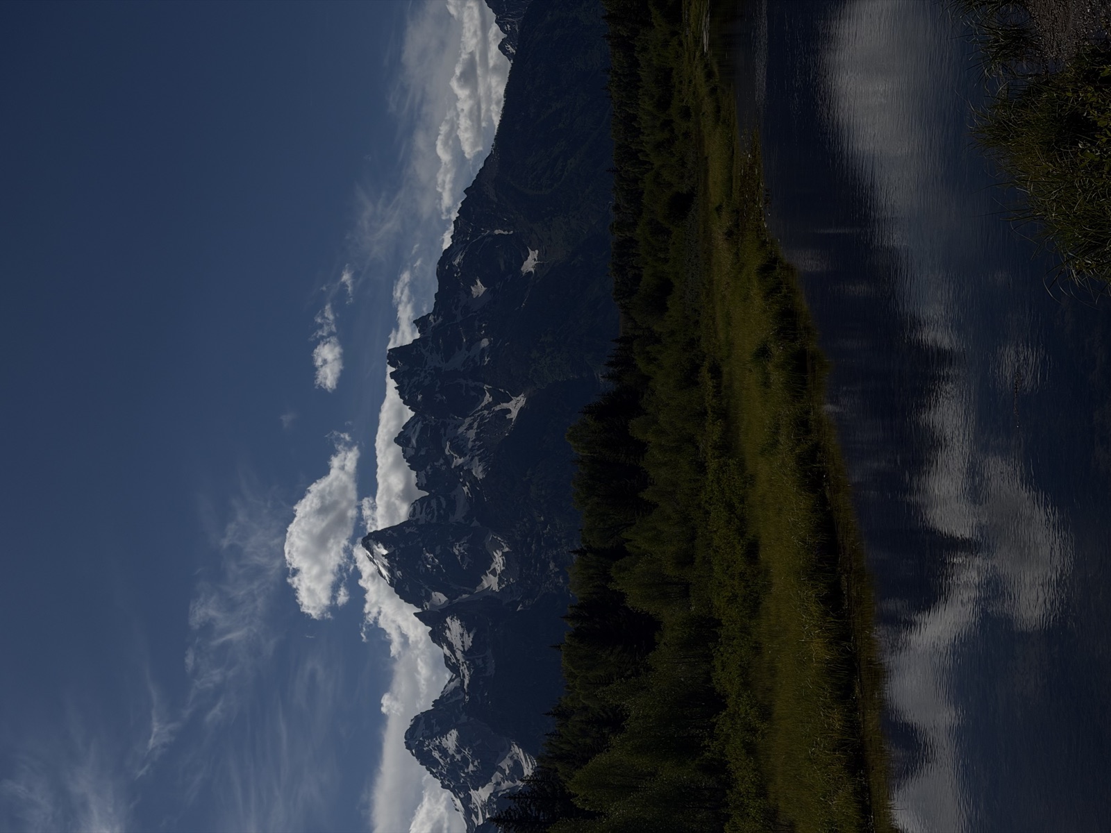 Jagged mountain peaks reflected in a dark, calm wetland