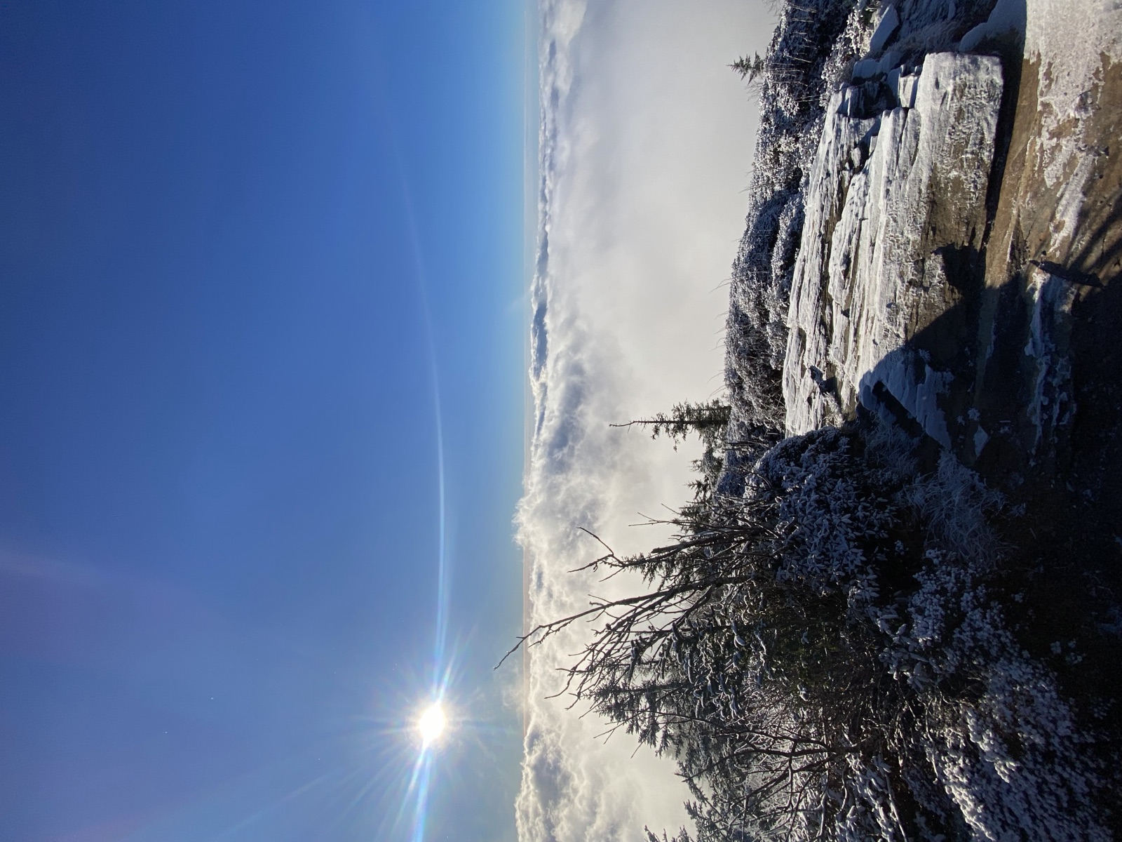 Sunlight over a snowy rock ledge and a sea of clouds