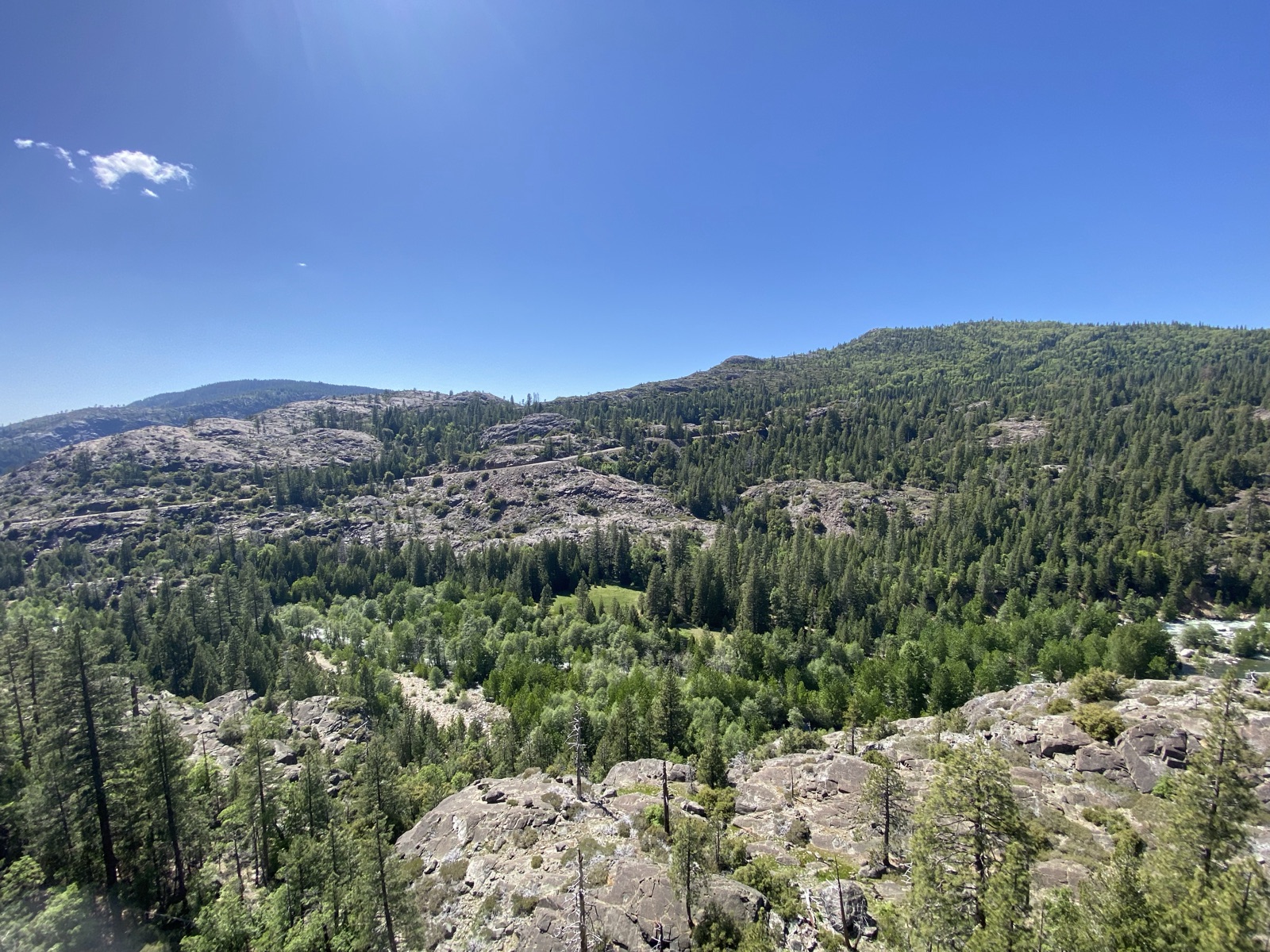 Forested granite ridges under a clear blue sky