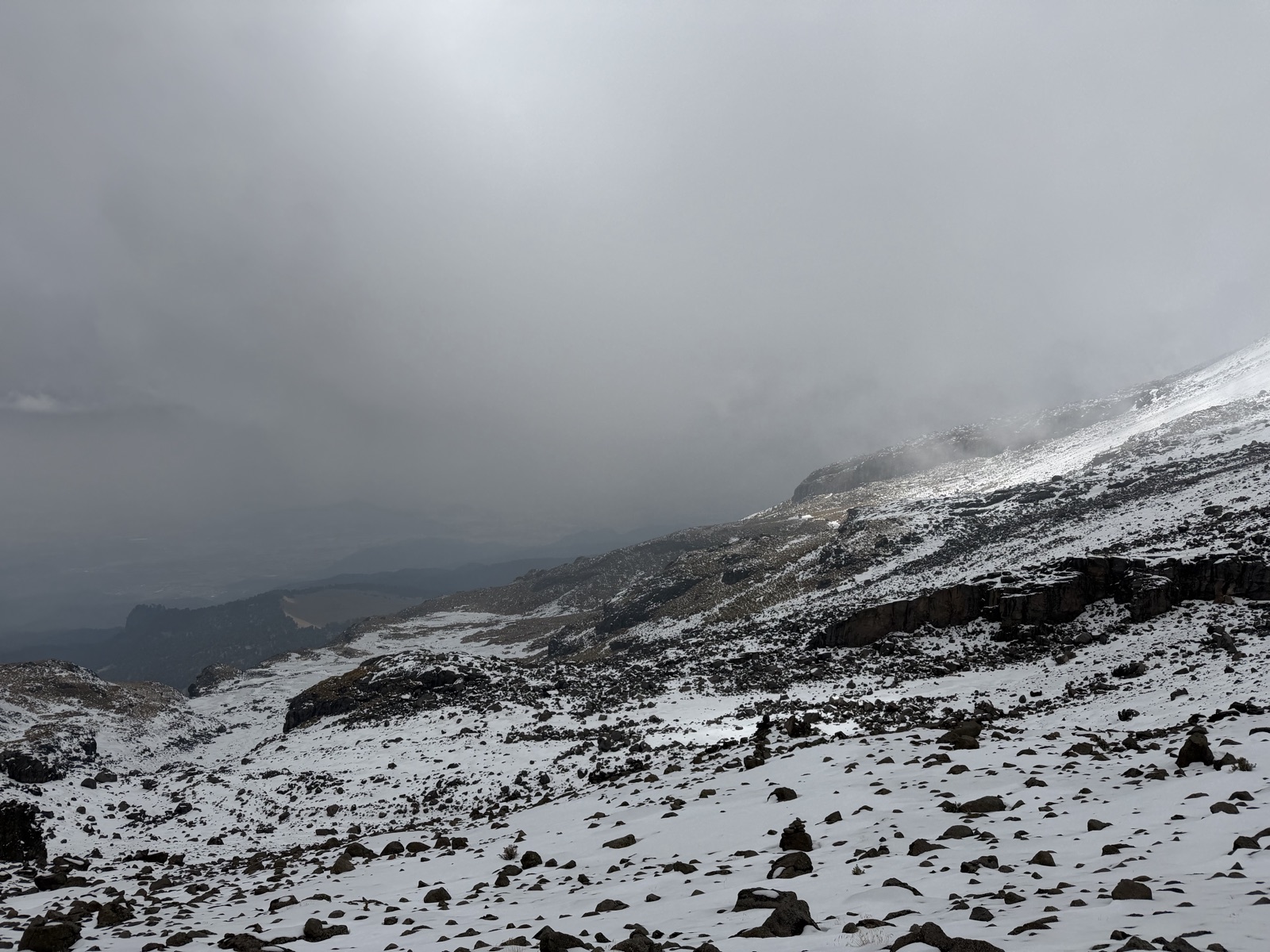 Snow-covered volcanic slope disappearing into dense fog