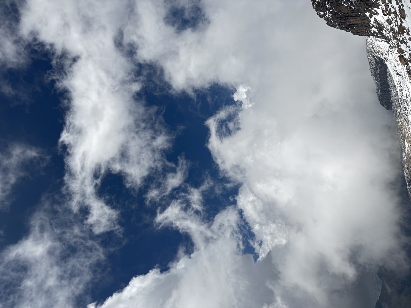 Clouds moving around a steep snow-dusted mountainside