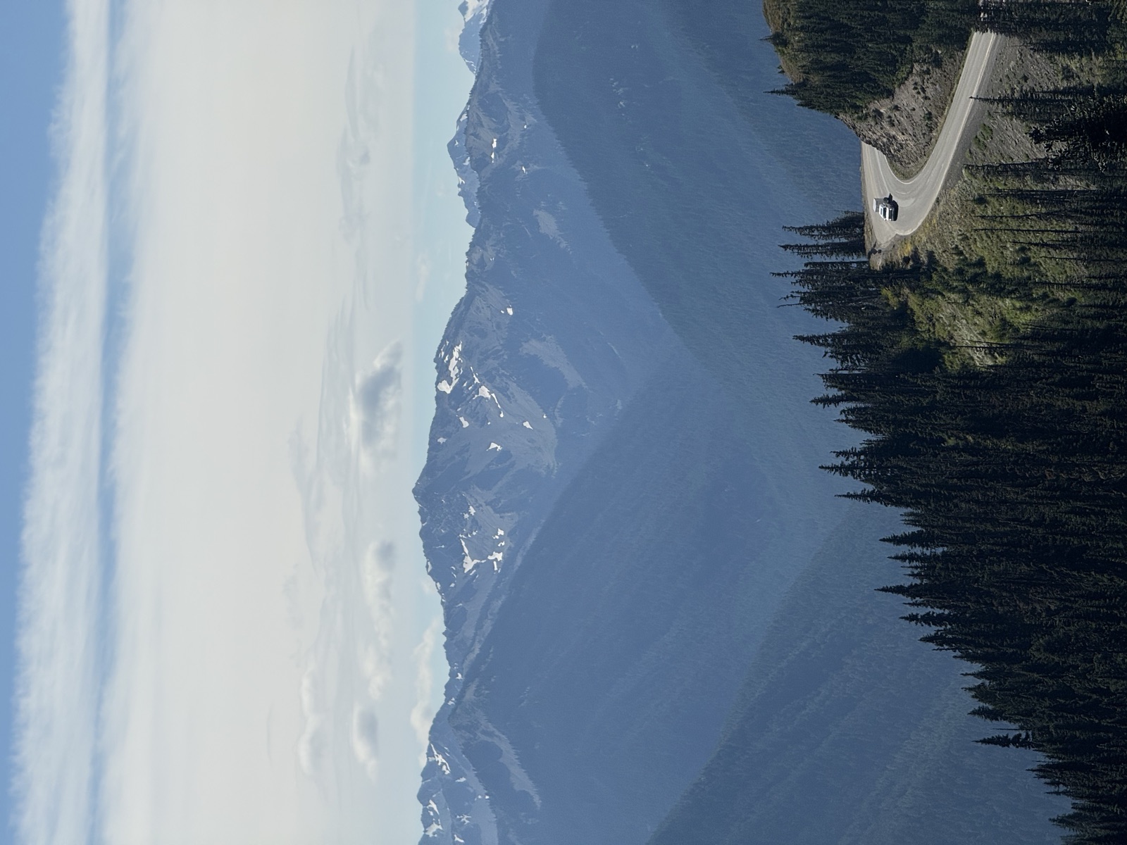Mountain road curling along a ridge below snow-streaked peaks