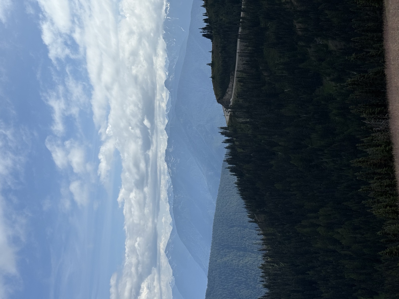 Layered blue mountain ridges beyond a curving high road